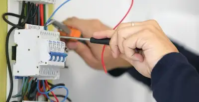 Electrician installing and adjusting circuit breakers in an electrical panel in Spokane, WA